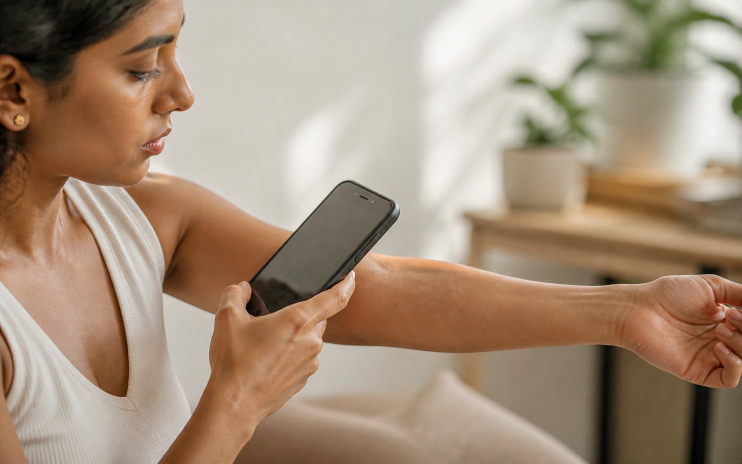 A mobile phone held close to skin in natural daylight, showing the form factor behind Dermos' nine-language, mobile-first dermatology diagnostic.